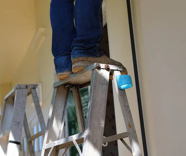 a man standing on the top step of a ladder with caution