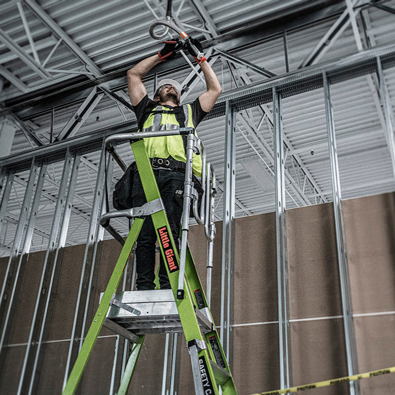 Person on a ladder working on a ceiling in an indoor construction setting