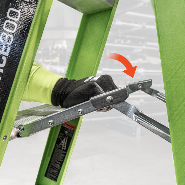 Green ladder with a hand wearing a black glove holding onto a spreader step, on a white background.