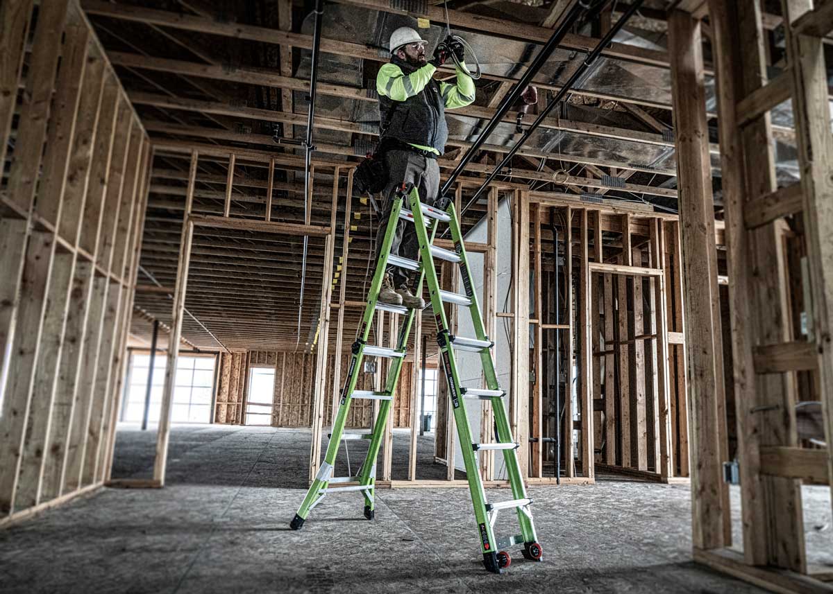 A man on a ladder in a construction building, working on a project