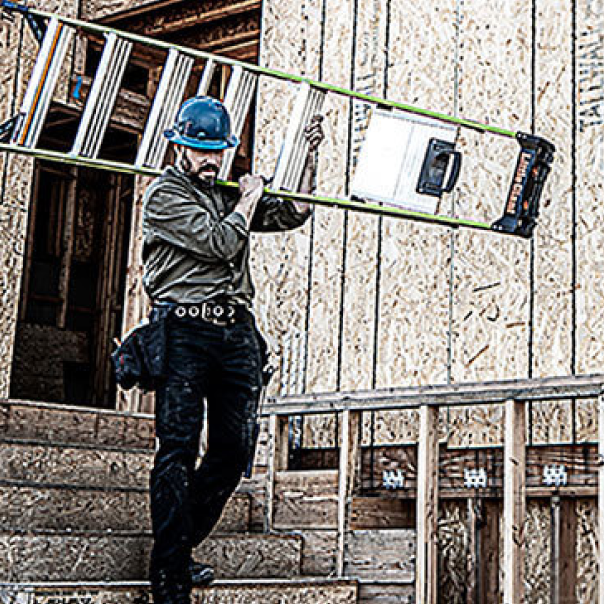 Constuction worker carrying Step ladder on his shoulder coming down stairs at construction site